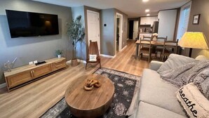 Un salon moderne comprenant un canapé, une table basse, un téléviseur et un coin repas avec des chaises et une table.