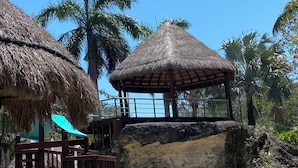 A playground with a slide, a thatched-roof structure, and a rock formation.