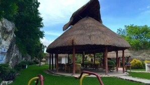 A thatched-roof gazebo with outdoor seating and exercise equipment.