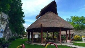 Un pabellón de techo de paja con asientos al aire libre y equipo de ejercicio.