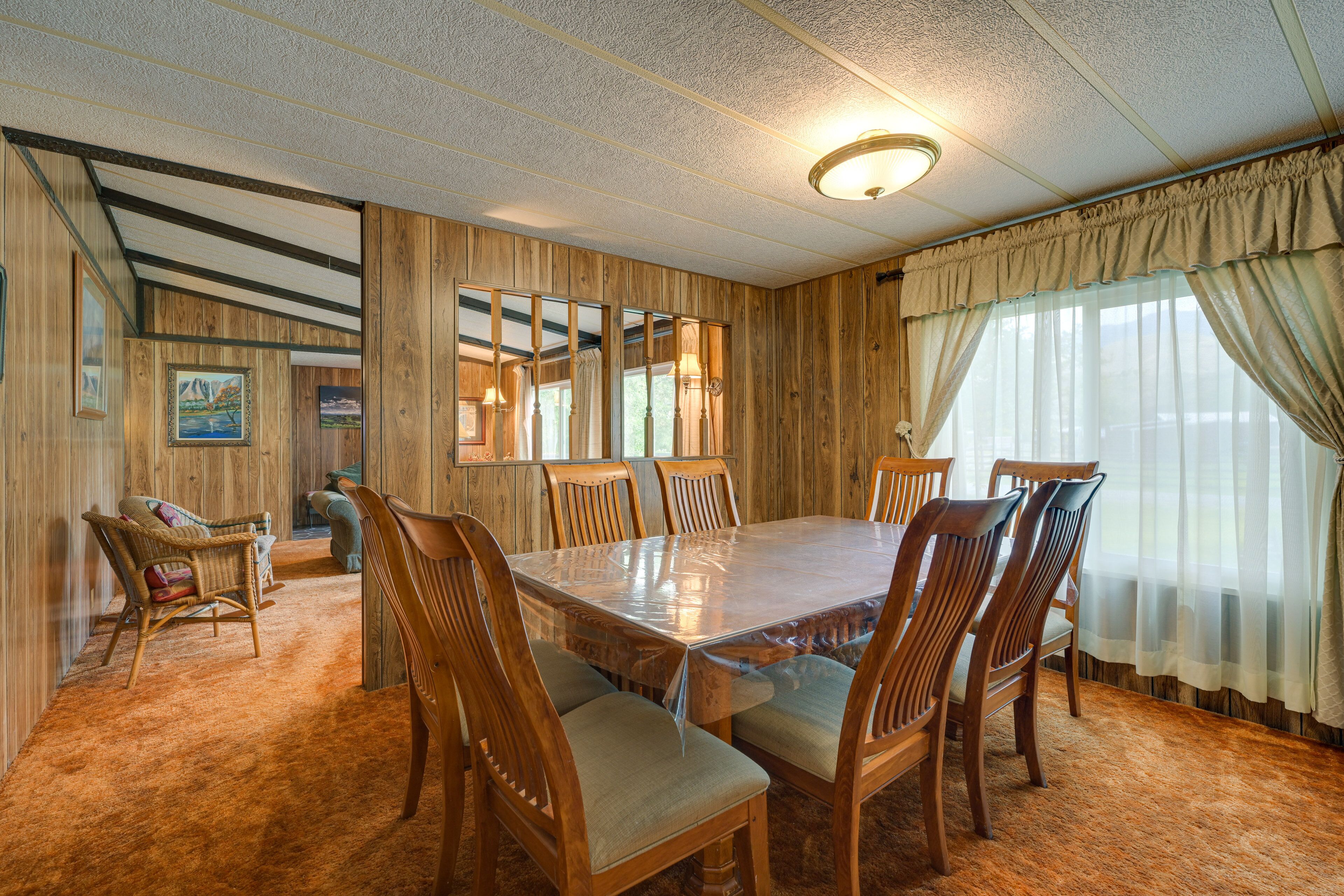 Une salle à manger avec une grande table en bois entourée de chaises, des murs en bois et un lustre.