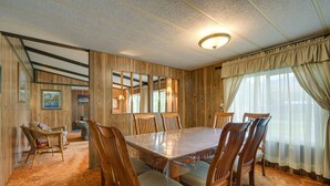 Una sala da pranzo con un grande tavolo in legno circondato da sedie, pareti in legno e un lampadario.