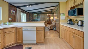 Una cucina compatta con mobili in legno, lavastoviglie e microonde.