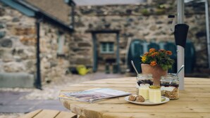A wooden table with a newspaper, jars of food, and a flower pot.