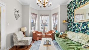 A living room with a green sofa, patterned armchair, and a coffee table. - The Battery Harbour Home, Ocean&City View,Parking (St. John's)