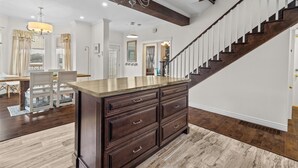 A spacious living area with a dark wood floor, a large dark wood cabinet, and a staircase with white railings. - The Battery Harbour Home, Ocean&City View,Parking (St. John's)
