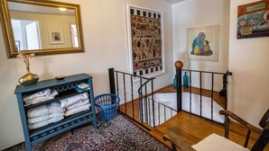 A staircase with a black railing, a blue basket, and a blue console table with towels. - Iconic Battery Cottage Signal Hill Sea&City Views (St. John's)