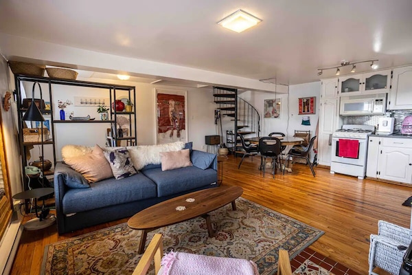 Seamless living on display: hardwood floors, a well-equipped kitchen, dining vibes, and a cozy wood fire stove. 🏡 Spiral staircase leads to dreamy bedroom upstairs.