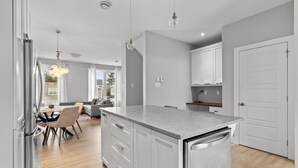 Una cocina moderna con una isla central, armarios blancos y un rincón de comedor con sofá y sillas.