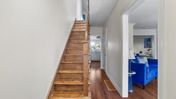 A wooden staircase leading to a living area with a blue sofa and a lamp.
