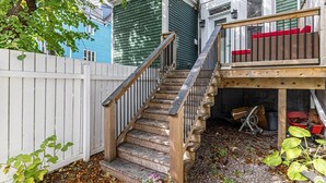 Eine Holztreppe führt zu einer Terrasse mit roten Kissen.
