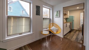 A room with large windows, a yellow chair, a small table, and a kitchen area. - The Bannerman Park Loft Private Parking King Bed (St. John's)