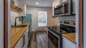 A compact kitchen with a sink, a teal refrigerator, a microwave, and a stove. - The Bannerman Park Loft Private Parking King Bed (St. John's)