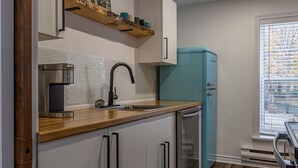 A compact kitchen with white cabinets, a wooden countertop, a built-in coffee maker, and a teal refrigerator. - The Bannerman Park Loft Private Parking King Bed (St. John's)