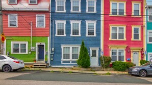 Una hilera de casas adosadas coloridas con estilos arquitectónicos diferentes y vista a la calle.