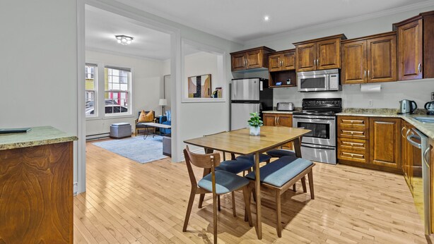 Una cocina moderna con armarios de madera, electrodomésticos de acero inoxidable y un comedor con mesa y sillas de madera.