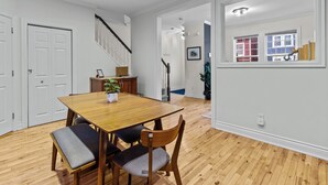 Un comedor con una mesa y sillas de madera, una escalera y vistas al exterior a través de una ventana.