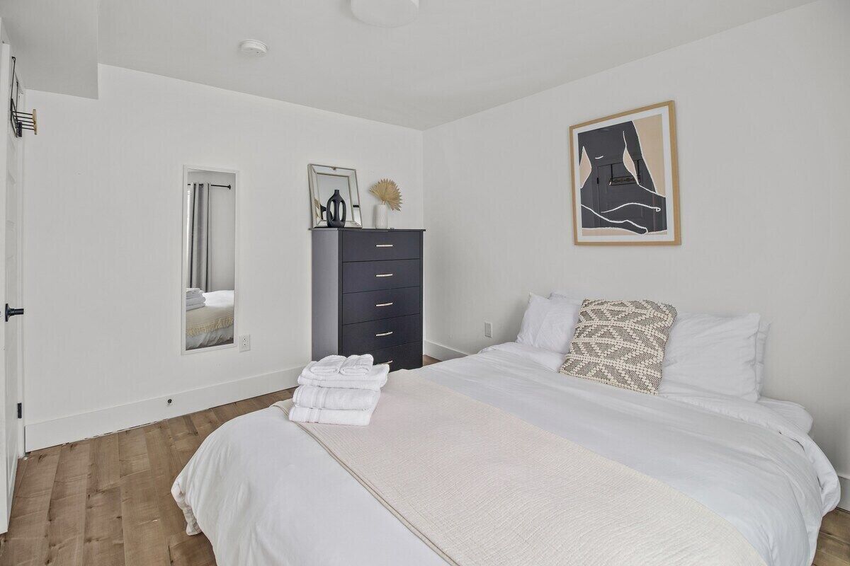 Un dormitorio con cama, cómoda, espejo y un cuadro en la pared.