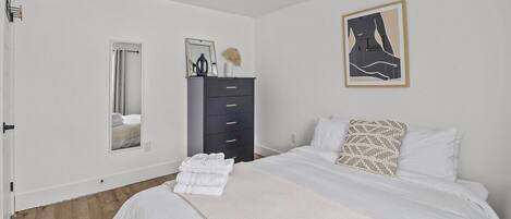 Un dormitorio con cama, cómoda, espejo y un cuadro en la pared.