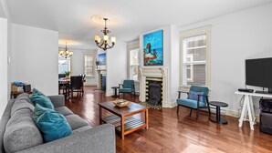A living room with a sofa, chairs, a fireplace, a painting, and a television. - Victorian 4BR 2.5BA 2Parking Near Parks & DT (St. John's)