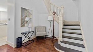 A staircase with white railings, a grey chair, a floor lamp, and a small table with a lamp. - Victorian 4BR 2.5BA 2Parking Near Parks & DT (St. John's)