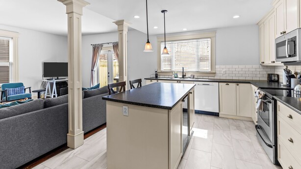 A modern kitchen with a central island, white cabinetry, and stainless steel appliances. - Victorian 4BR 2.5BA 2Parking Near Parks & DT (St. John's)