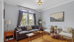 Un salon avec un canapé, des fauteuils, une table basse et un plancher en bois.