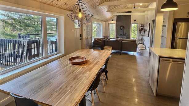 A modern kitchen with a wooden ceiling, large windows, and a central island. - A 30 Minutes de St-sauveur, Chalet Tout Équipé, Spa, Bord de lac (Gore)