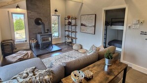 A cozy living room with a fireplace, a sofa, a coffee table, and a bunk bed in the corner. - A 30 Minutes de St-sauveur, Chalet Tout Équipé, Spa, Bord de lac (Gore)