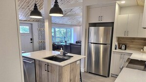 A modern kitchen with a central island, stainless steel appliances, and pendant lighting. - A 30 Minutes de St-sauveur, Chalet Tout Équipé, Spa, Bord de lac (Gore)
