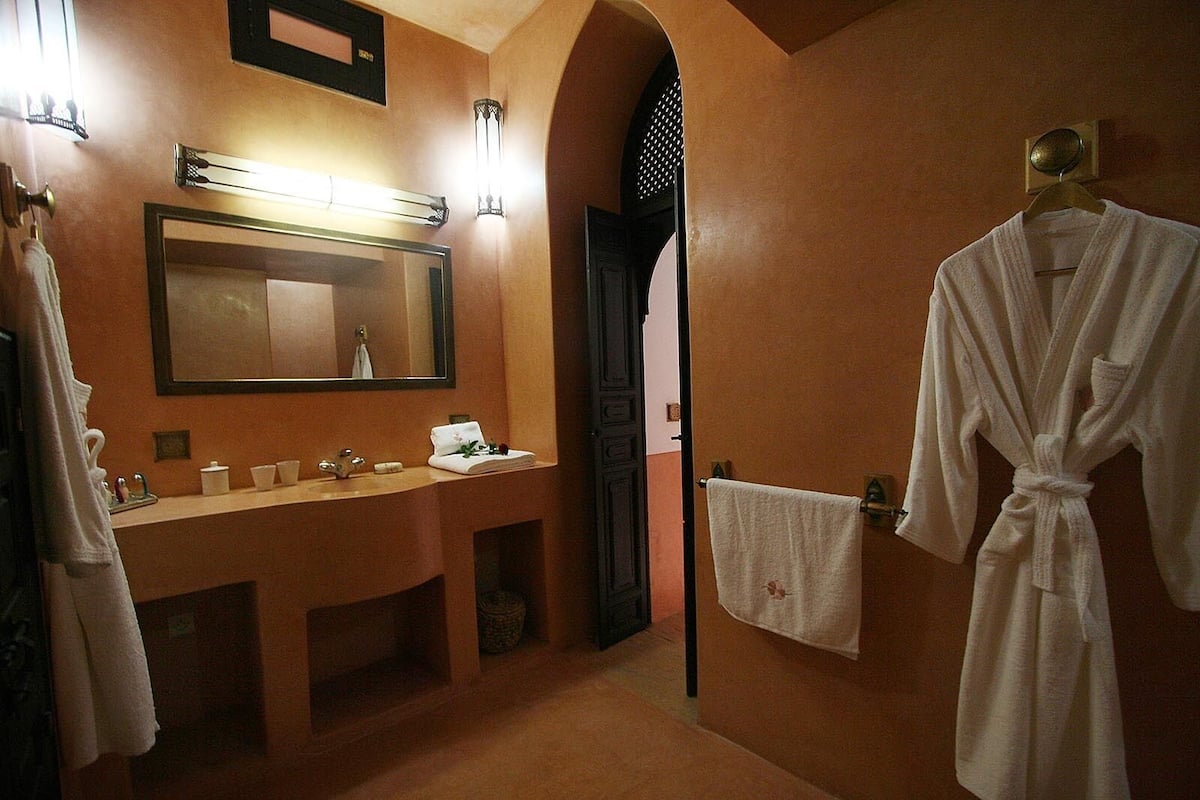 A bathroom with a large mirror, a sink, and two towels hanging on the wall.