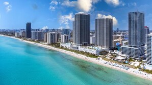 A coastal cityscape with high-rise buildings, a beach, and clear blue skies. - ★★★★★ Stylish Retreat at Lyfe Resort Steps Away from the Ocean with Rooftop Pool (Hollywood)
