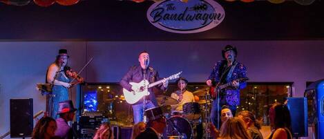 A band performing on stage with a sign that reads "The Bandwagon."