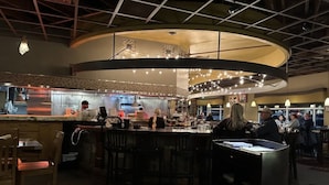 A restaurant with a curved bar area, multiple seating options, and a visible kitchen in the background. - Designer Apt With Jacuzzi Sky Lounge Gym Access (Sparks)