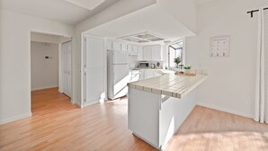 A modern kitchen with white cabinetry, a central island, and a ceiling light fixture. - Delightful 4BR Home Nr Downtown Reno w Fireplace (Reno)
