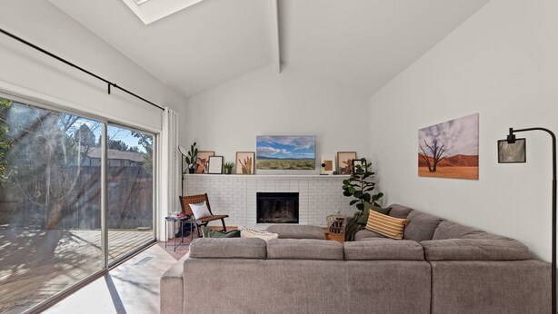 A modern living room with a large gray sectional sofa, a fireplace, and a large window overlooking a deck. - Delightful 4BR Home Nr Downtown Reno w Fireplace (Reno)