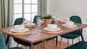 A dining table set with white bowls and plates, green chairs, and a woven placemat. - Delightful 4BR Home Nr Downtown Reno w Fireplace (Reno)