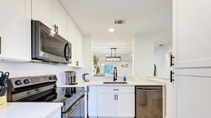 Una cocina moderna con armarios blancos, electrodomésticos de acero inoxidable y una isla central.