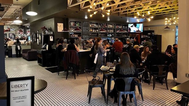 Un espace bar animé, avec un sol à carreaux, un comptoir et un panneau indiquant qu’il n’y a pas de service en libre-service.