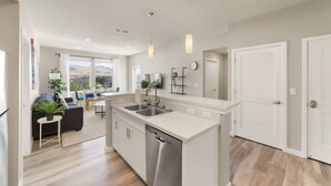 A modern kitchen with a dishwasher, double sink, and pendant lights. - Chic Apt w Jacuzzi Pool BBQ Mountain Views (Sparks)