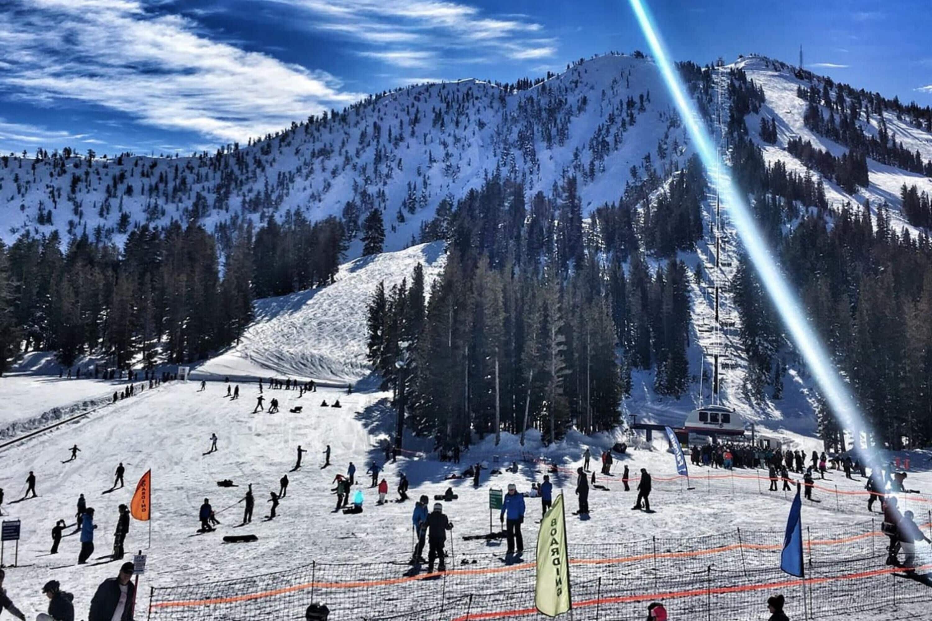 Una stazione sciistica con montagne innevate sullo sfondo, impianti di risalita e sciatori.