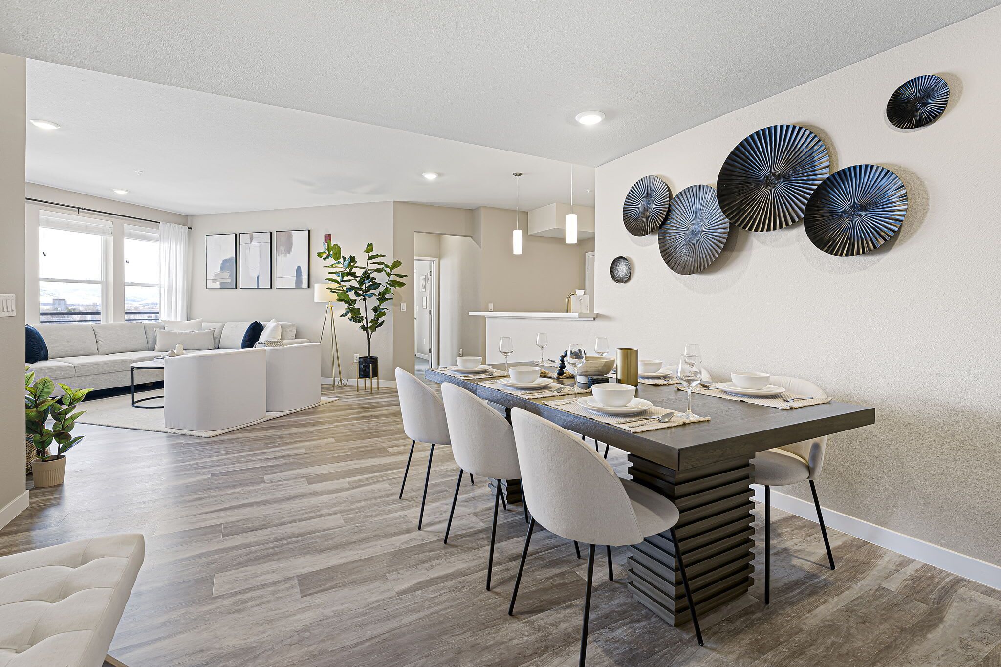 Un espace de salle à manger moderne avec une longue table, des chaises blanches et une œuvre d’art contemporaine accrochée au mur.