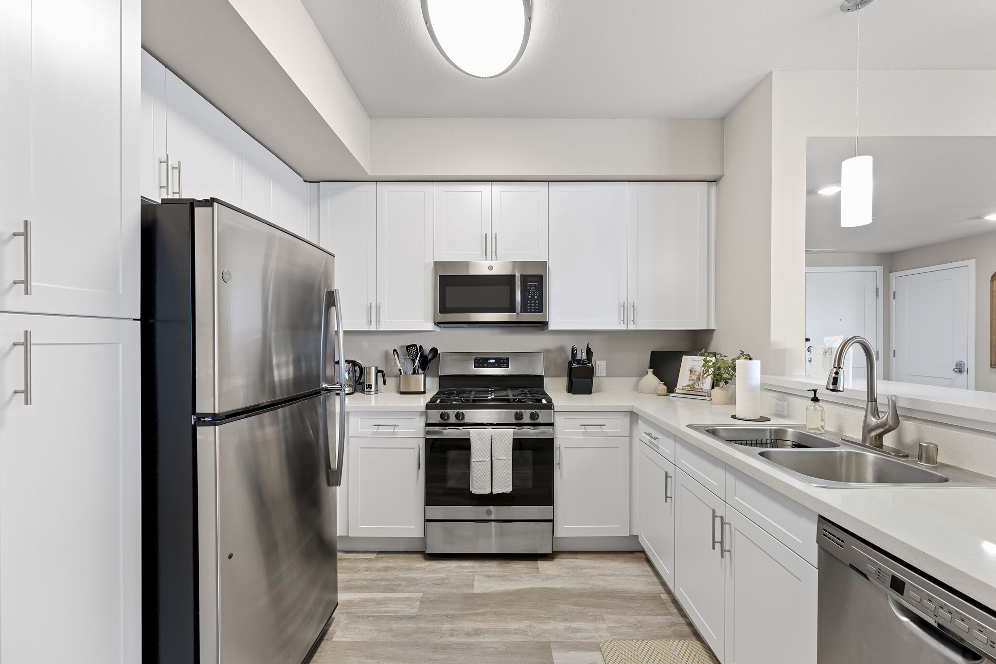 A modern kitchen with stainless steel appliances, white cabinetry, and a central island with a sink and countertop.