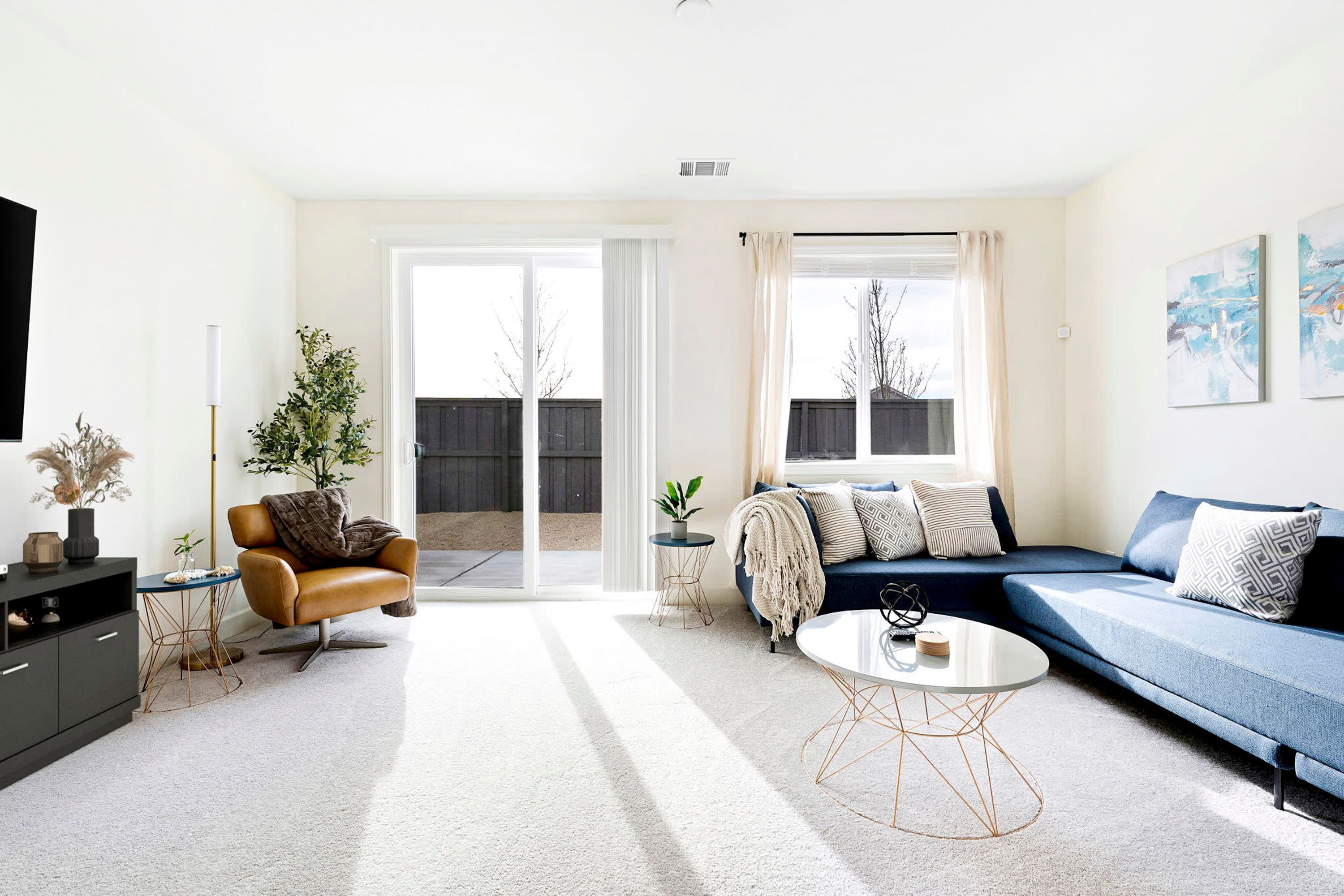 Een moderne woonkamer met een bank, fauteuil, salontafel en een televisie.