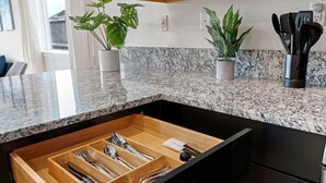 A kitchen with a granite countertop, wooden drawer, and potted plants. - Stylish Sleek 4BR Nevada Home Near Downtown Reno (Sparks)