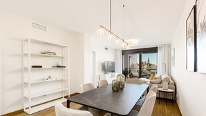 Un comedor moderno con una mesa de mármol, sillas blancas y una estantería.