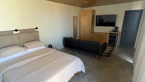 A bedroom with a large bed, a sofa, a TV, and a wardrobe. - MILU-CABAÑA SENCILLA (Guadalupe)