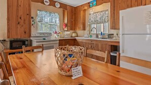 A kitchen with wooden cabinets, a microwave, stove, and a dining table with chairs.