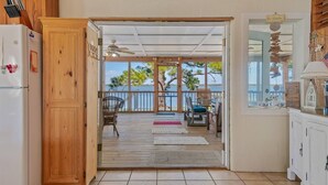 A kitchen with a wooden door leading to a covered outdoor area with a view of the water.