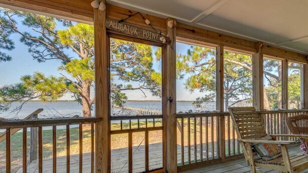 A wooden deck with a rocking chair and a sign reading "Alligator Point".